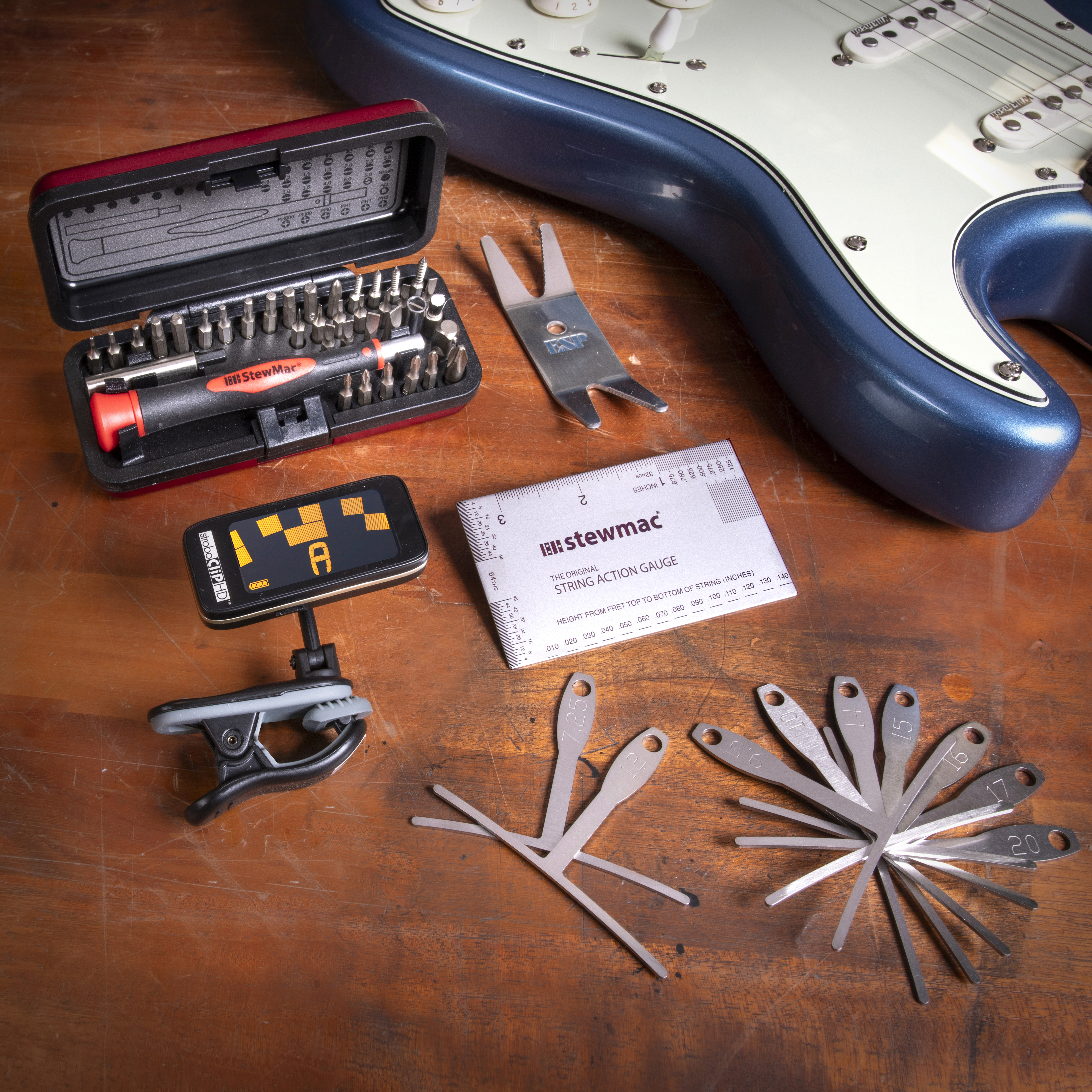 Herramientas utilizadas en la configuración de guitarra en el banco de trabajo con la guitarra azul Stratocaster.