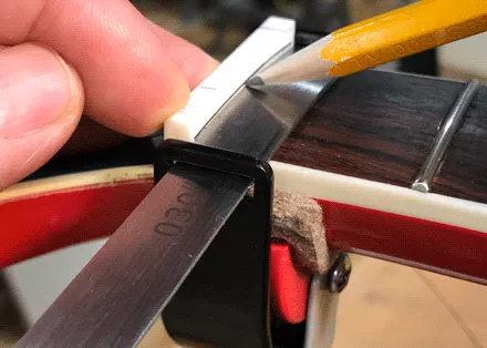 Marcar la altura del traste con galgas de espesores en la ranura de seguridad