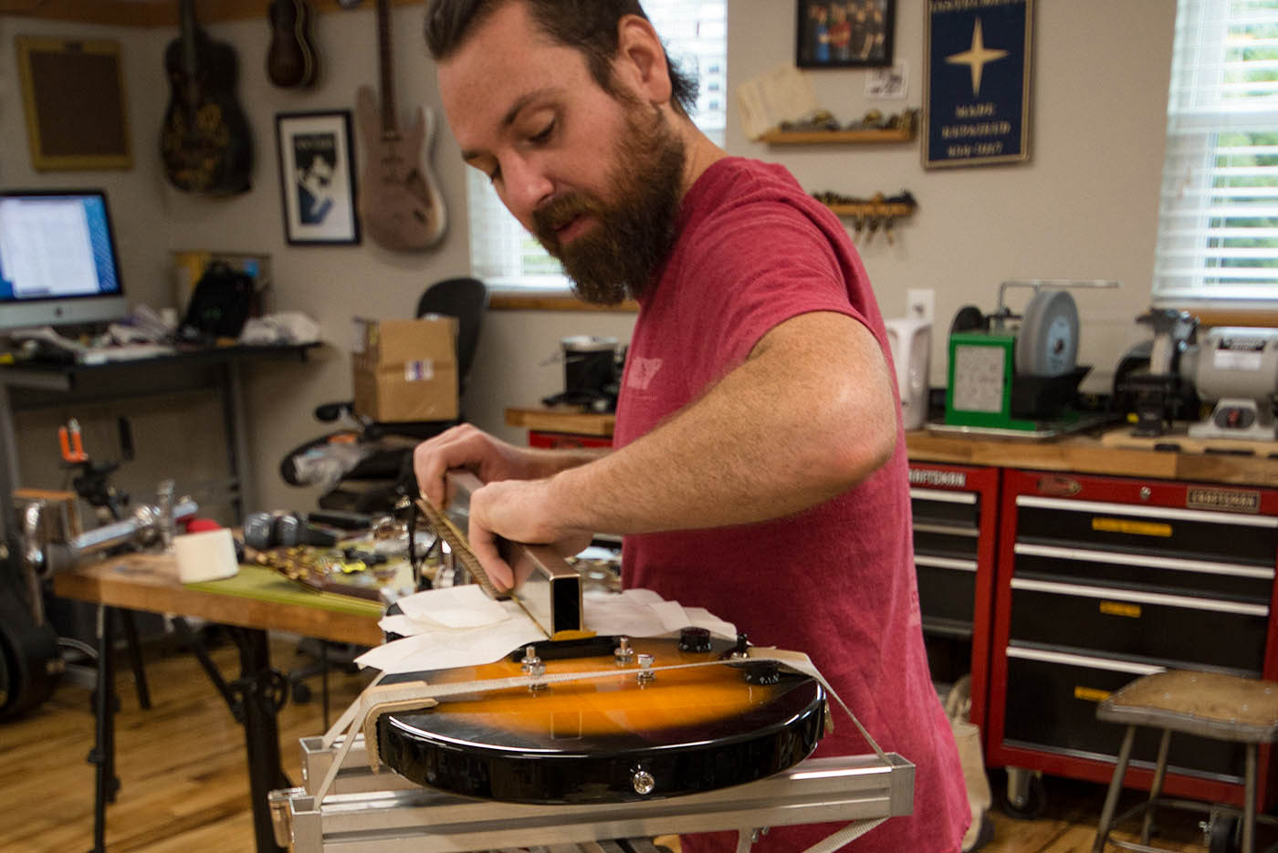 Hombre nivelando trastes con Fret/diapasón Nivelador en plantilla de mástil