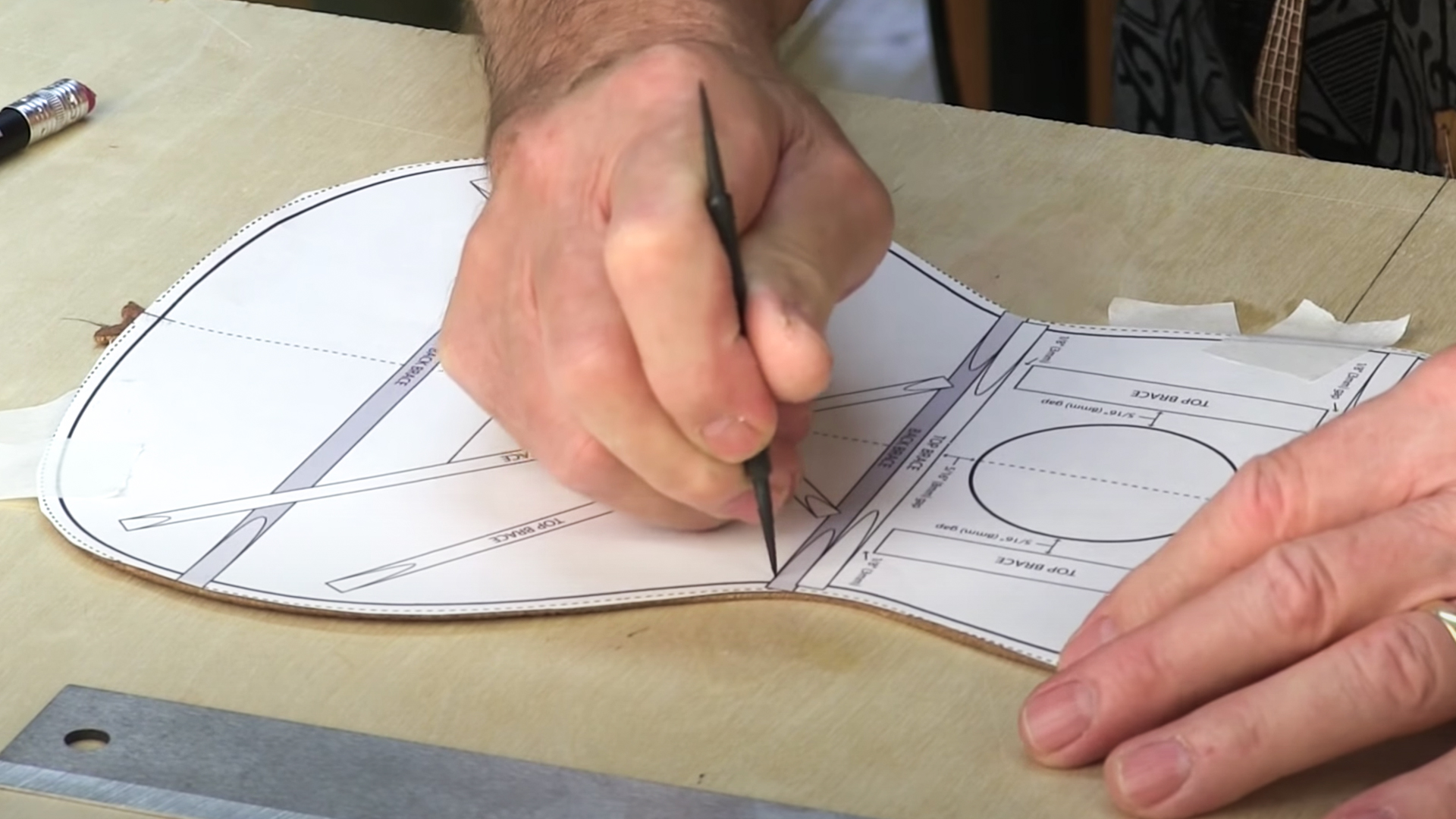 Manos trazando patrón de ukelele con escritura