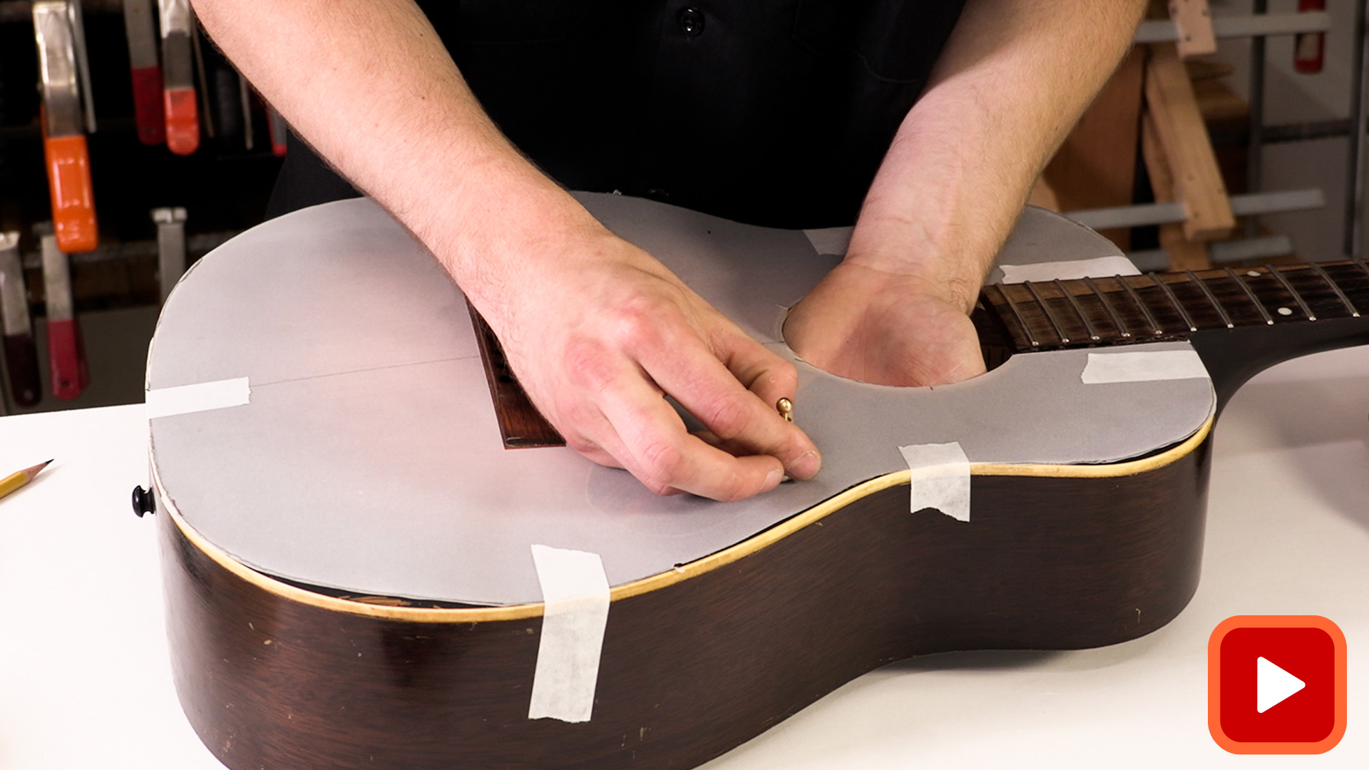 Manos pegando papel de calcar a la parte superior de la guitarra acústica